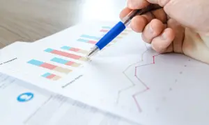 Main d'une personne pointant un graphique avec un stylo bleu. L'image illustre la veille informationnelle def.