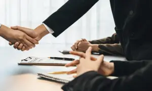 Poignée de main lors d'un entretien d'embauche, avec un CV sur la table. Peut-être discutent-ils d'une clause de sortie conjointe.