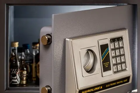 Coffre fort numérique gratuit ouvert, révélant des petites bouteilles. Clavier électronique pour un accès sécurisé.