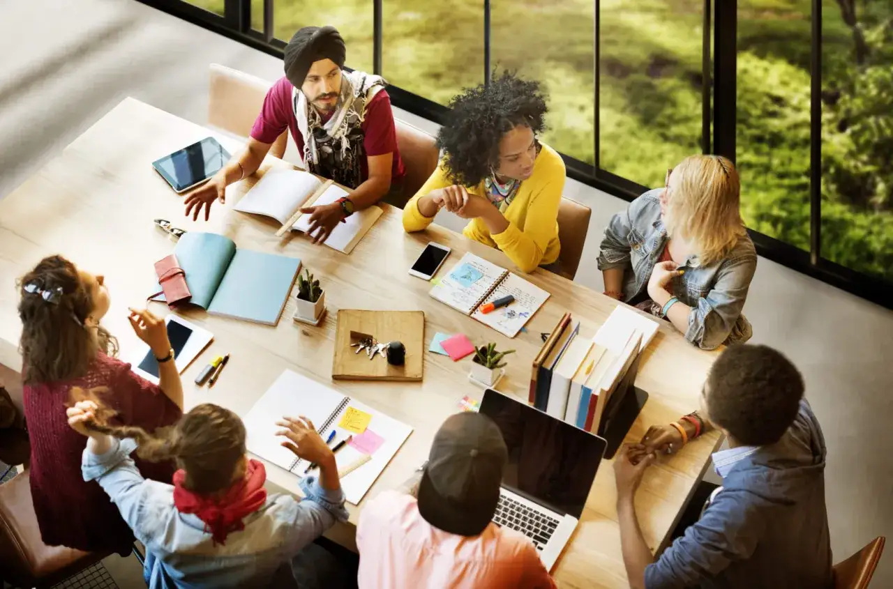Des &eacute;tudiants discutent autour d'une table, illustrant le travail collaboratif, d&eacute;finition de l'&eacute;change d'id&eacute;es pour un projet commun.