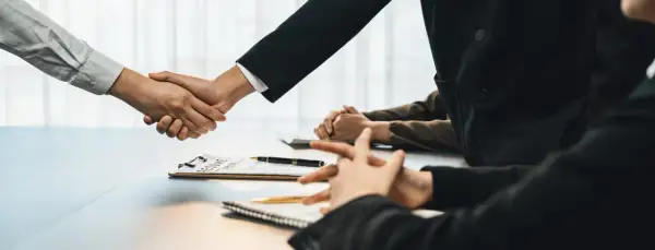 Poignée de main lors d'un entretien d'embauche, avec un CV sur la table. Peut-être discutent-ils d'une clause de sortie conjointe.